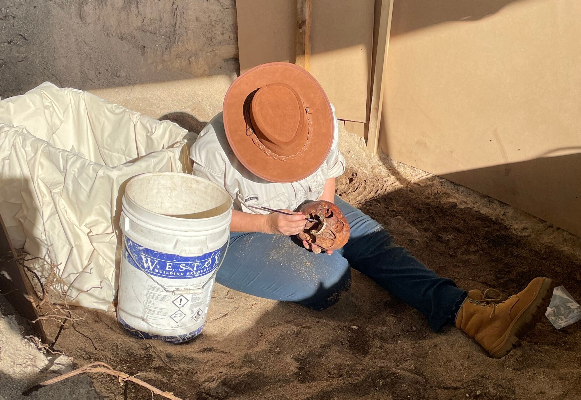 140 year grave brushing away sand artefact