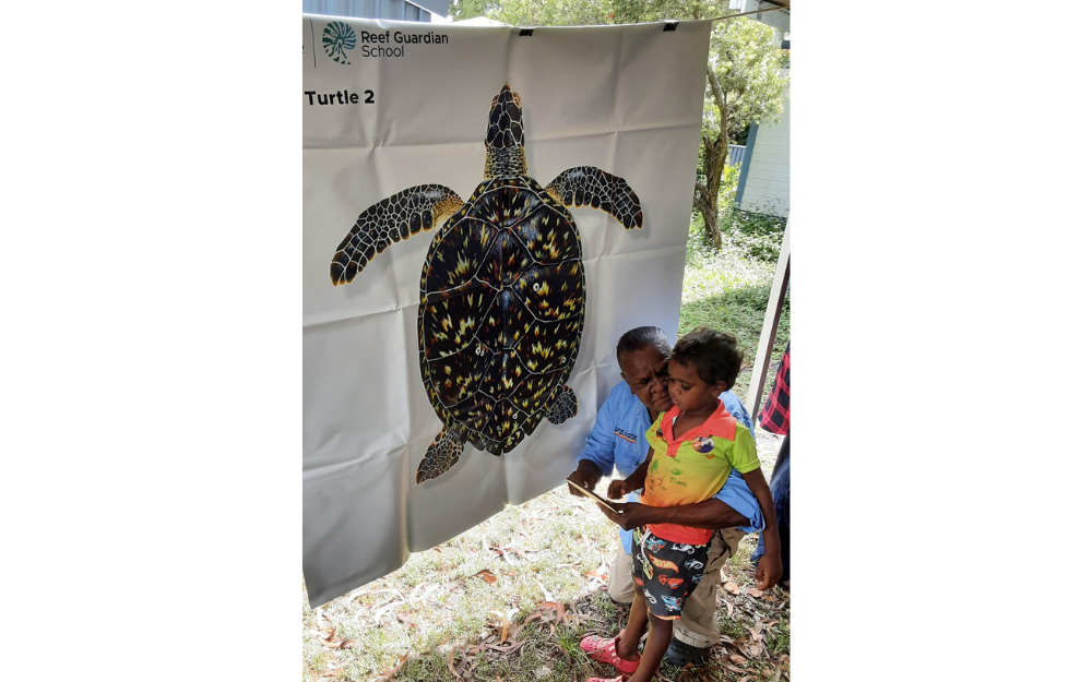 A Lama Lama ranger crouches to teach a young toddler about turtles.