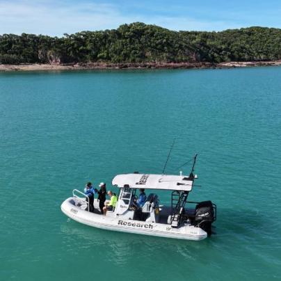 A research boat anchors at a project location with a vegetated island scene in the background