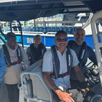 A photo of four researchers smiling on a boat docked at a marina