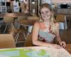A woman sits at a table with a map on it
